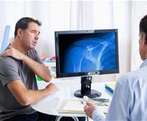 man holding his shoulder in doctor's surgery