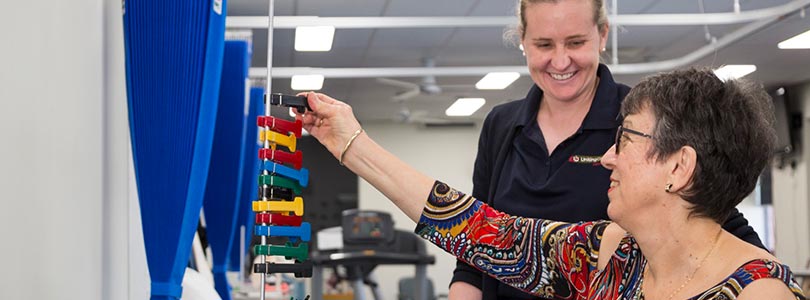 A smiling allied health professional supports a patient in her rehabilitation journey.